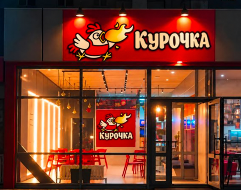 Вход в ресторан «Курочка»: красная вывеска и тёплый свет внутри